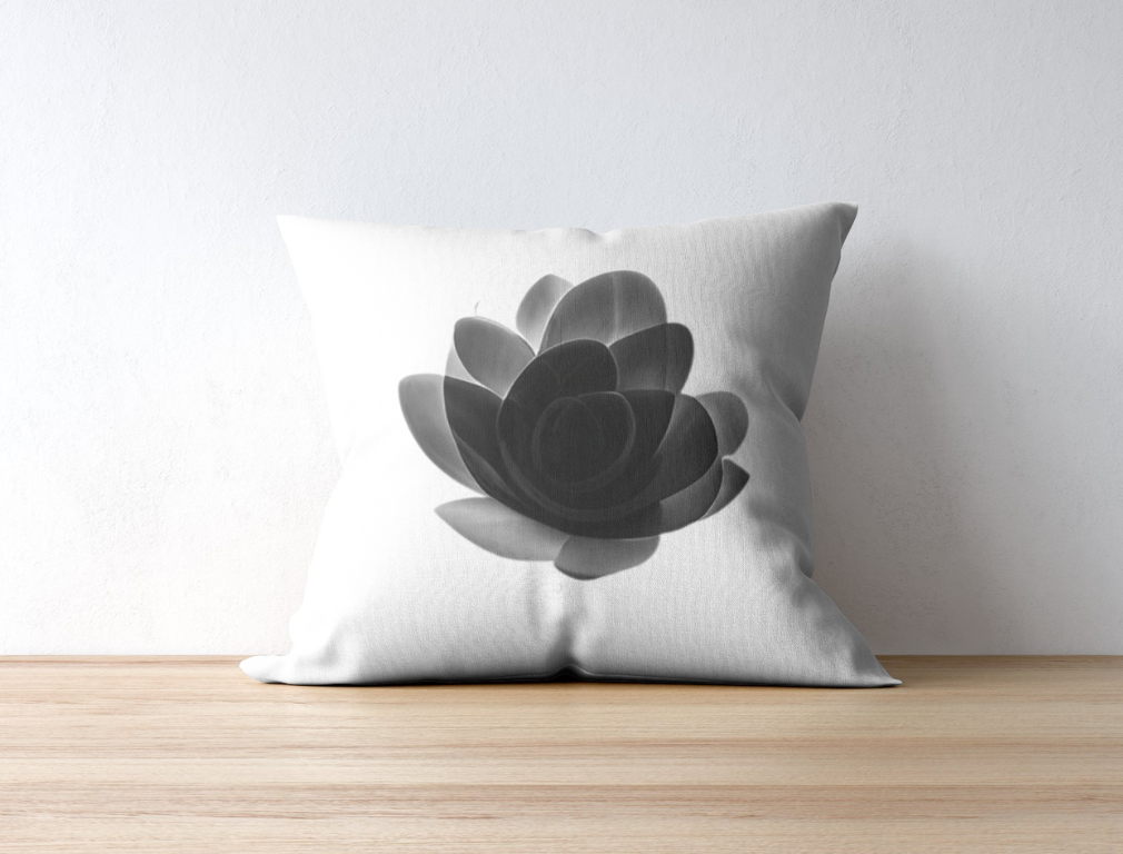 White pillow with black rose petals, sitting on the hardwood floor.